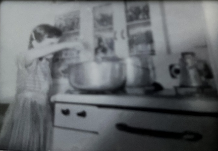 Vintage snapshot (1950s) of girl stirring pot of soup